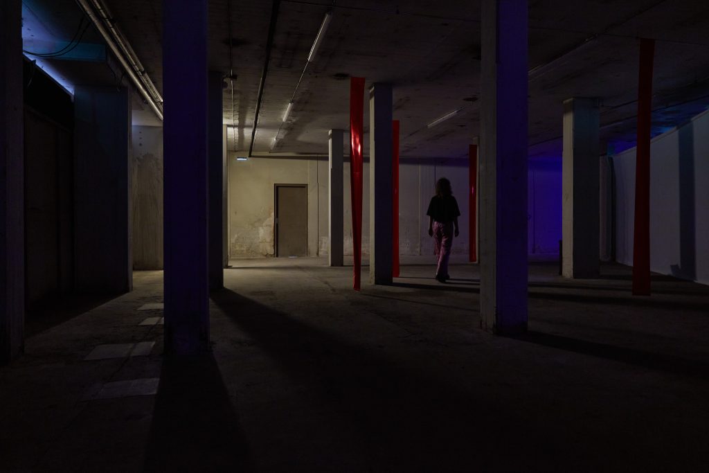 person walking in art installation, dark basement