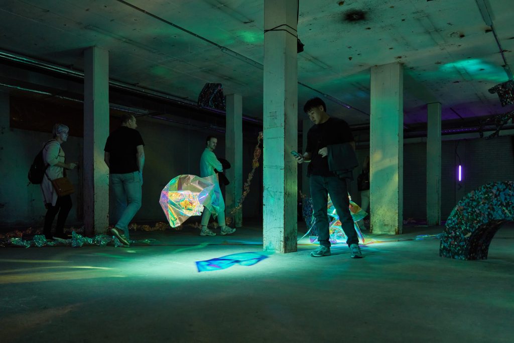 people looking at the multicoloured floating objects, blue reflections, making photographs