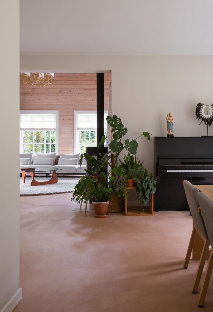 eethoek met piano, veel planten, doorkijkje naar woonkamer, grote zitbank, lekker kleed en haardje